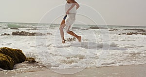 Side view of African american woman playing with sea water on the beach 4k