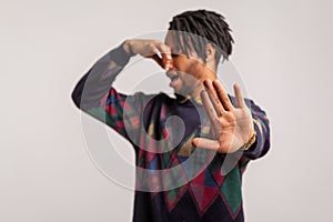 Side view african man with beard and dreadlocks showing no gesture with palm holding breath with fingers on nose, feeling