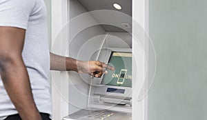 Side view of african man touching screen on ATM