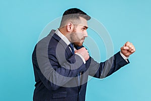 Side view of aggressive businessman wearing official style suit being ready to punch, boxing with