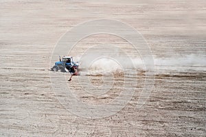 Side view of agricultural industrial tractor plows soil field for sowing , aerial view. Land cultivation