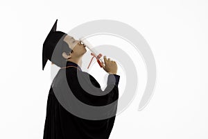 Side view of Asian Graduate man in cap and gown smile and kissing certificated or diploma