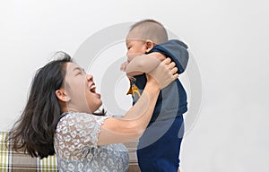 Side view of asian mother lifting and playing with newborn baby