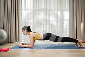 Side view of Asian young woman in sportswear with plank position exercise for healthcare slim and body weight control at home