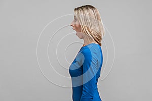 Side view of astonished beautiful woman looking left with stunned shocked face. isolated on gray background