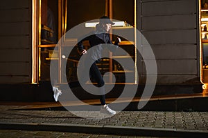 side view on athlete female running past city cafe at night, sport outdoors