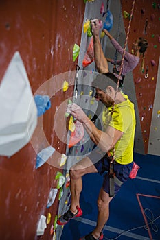 Side view of athletes rock climbing in fitness club