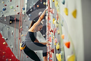 Side view of athletic woman climbing indoors