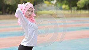Side view athletic young asian muslim woman in sportswear standing and lifting dumbbells outdoor for morning exercise