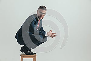 Side view of attractive man in his forties crouching on wooden chair