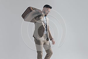 Side view of attractive man with suitcase over shoulder looking down
