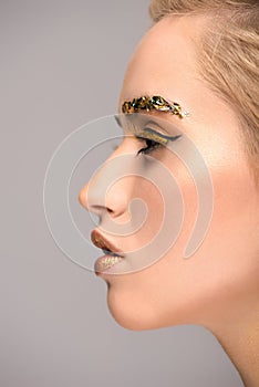 side view of attractive woman with golden glittering makeup