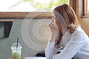 Side view of attractive young Asian business woman waiting something in coffee shop