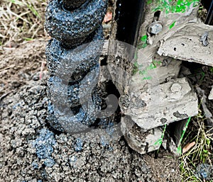 Side view of a auger for water level drilling, filled with oilish sand and gravel, hard work