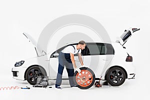 side view of auto mechanic in blue uniform changing car tire