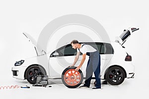 side view of auto mechanic pushing tire to change old one photo