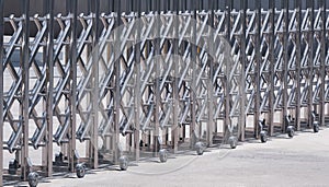 Side view of automatic stainless steel barrier gate or folding fence gate in front of office building