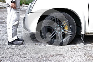 Side view of automotive mechanic man in white uniform holding wrench in his hands ready to repairing car engine.