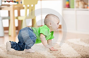 Side view of baby crawling on carpet on floor in children room