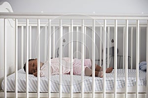 Side View Of Baby Girl Sleeping In Nursery Cot