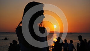 Side view of back light of a woman silhouette warm sunset in front of sun