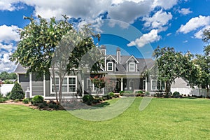 The side view of the backyard of a large gray craftsman new construction house with a landscaped yard