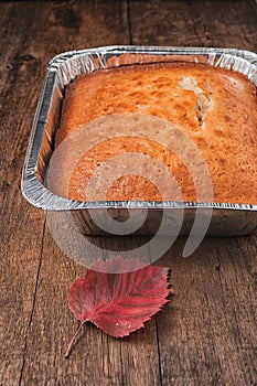 Side view of a baked pie in the form of thick aluminum foil on a wooden table