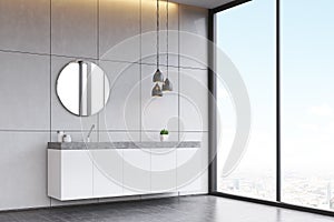 Side view of a bathroom sink with round mirror on tiled wall, co