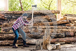 side view of bearded lumberjack in checkered shirt chopping log photo