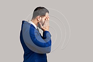 Side view of bearded man closing eyes with hand, dont want to see that, ignoring problems.