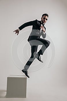 Side view of bearded man in tuxedo jumping to new beginnings