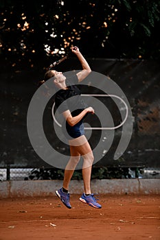 side view of beautiful bouncing woman tennis player with tennis racket in hand doing pitch