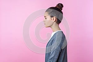 Side view of beautiful brunette teenage girl standing with serious expression. pink background, copy space