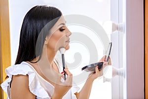 Side view beautiful dark hair girl putting on makeup on