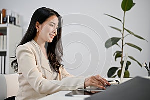 Side view of a beautiful Asian businesswoman working on her project on laptop