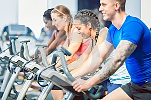 Side view of a beautiful woman smiling while cycling during spinning class