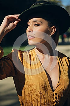 Side view of beautiful woman wearing hat and confidently looking away. Gorgeous model posing outdoor