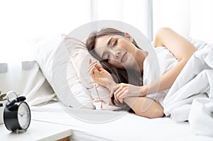 Side view of beautiful young Asian woman smiling while sleeping in her bed and relaxing in the morning. Lady enjoying sweet dreams