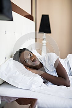 Side view of beautiful young smileAfro American woman smiling while sleeping in her bed at home