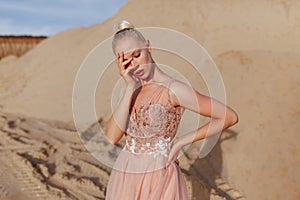 Side view of a beautiful young woman posing in the desert, with closed eyes, covered her face with her hand.