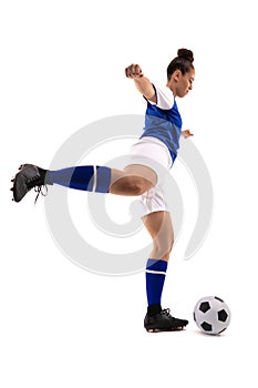 Side view of biracial young female soccer player kicking soccer ball while playing soccer