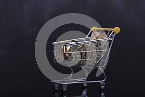 Side view of bitcoin and shopping cart on black background. Buying or selling the cryptocurrency concept. Virtual money