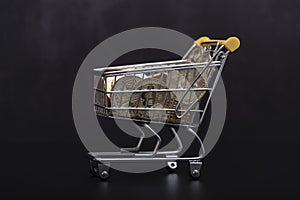 Side view of bitcoin and shopping cart on black background. Buying or selling the cryptocurrency concept. Virtual money