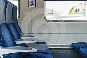 Side view of blue armchairs in empty train in row of three, no people in wagon,