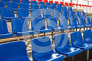 Side-view of blue and red plactic seats on sport stadium`s grandstand
