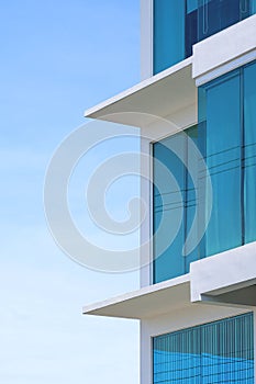 Blue roller blinds inside of glass wall of modern office building against blue sky in vertical frame