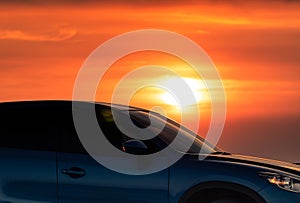 Side view of blue SUV car with sport and modern design parked on concrete road by sea beach at sunset. Electric car technology.