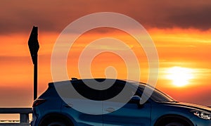 Side view of blue SUV car with sport and modern design parked on concrete road at sunset. Hybrid and electric car technology.