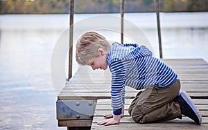 Side view of boy on dock looking in lake