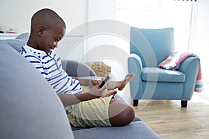 Side view of boy using mobile phone while sitting on sofa